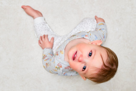 Portrait of a crying toddler boy sitting on the floor. Face of an unhappy child with tears in his...