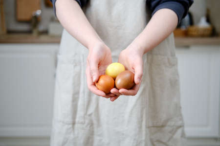 Woman holding glazed Easter cakes decorated with chocolate and sweets, home kitchen backgroundの写真素材