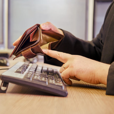 A businessman man with an empty wallet without money in his hands is working on a computer keyboard...