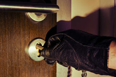 Man hand in a black glove opens the office door in the night light of a flashlightの写真素材