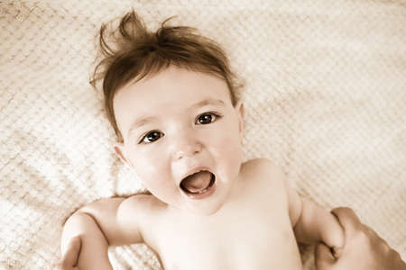 Scared screaming toddler baby boy with fear in his eyes. Unhappy child close-up on a white blanket. Kid aged one year (12 months)の写真素材