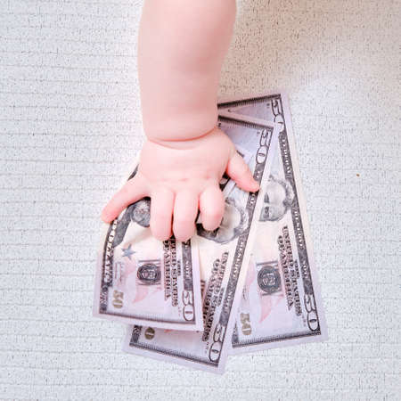 Baby hand and money US dollars, close-up. Children fingers and an object on a white backgroundの写真素材