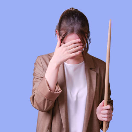 Woman teacher with headache on studio blue background, copy spaceの写真素材