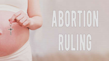 Text about the rules of abortion and chained hands of a pregnant woman, home living roomの写真素材