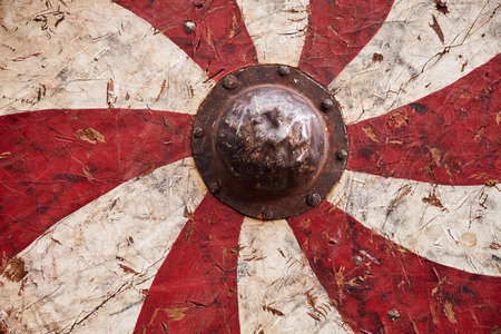 Red vintage shield with white spiral stripes a medieval warrior. Reconstruction of the events of the Middle Ages in Europeの写真素材
