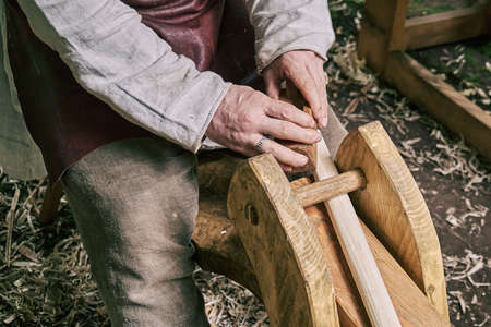 A man in medieval clothes makes a spear shaft. Reconstruction of the events of the Middle Ages in Europe.の写真素材