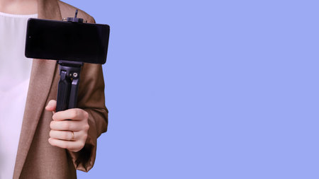 Woman teacher with phone for online lesson on studio blue background, banner copy space