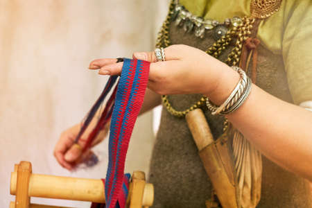A woman in ancient Byzantine clothing makes yarn and sews from vintage fabric threads. Reconstruction of the events of the Middle Ages in Europe.の写真素材