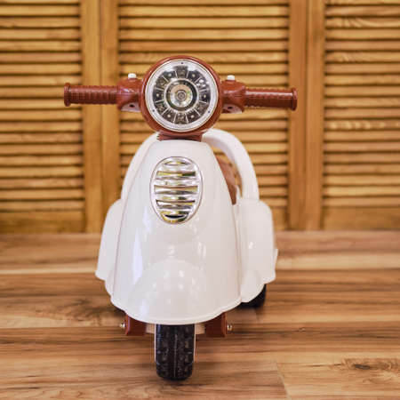 Plastic children motorcycle riding in the playroom, toy brown moped for kidの写真素材