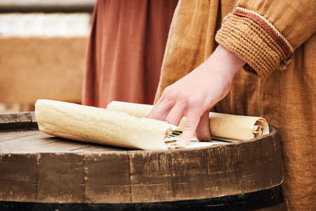 A man in vintage medieval clothes with a paper letter in his hand. Reconstruction of the events of the Middle Ages in Europeの写真素材