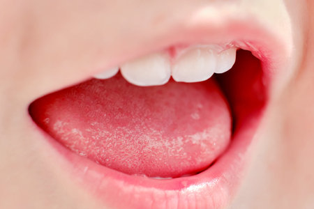 Upper teeth and baby tongue age one year close-up, child mouth macro photo