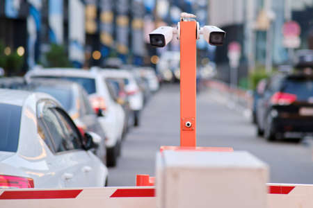 A security camera and a barrier at the entrance to the courtyard of residential houses. CCTV in a private parking lot in front of multi-storey buildingsの写真素材