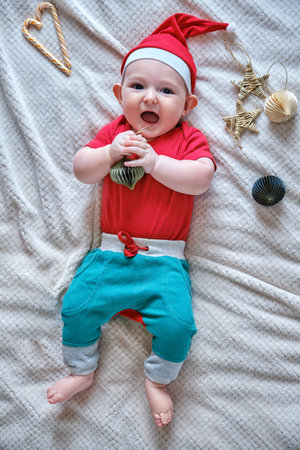 Baby infant boy in Santa hat with Christmas decorations on a white blanket. A child aged six months, New Year flat lay top viewの写真素材