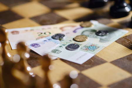 Chinese yuan money on the background of a chess board. Banknotes and coins of yuan from China on chessboardの写真素材