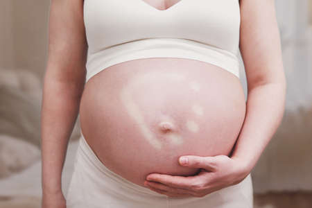 Pregnant woman and hand mark on tummy, home living roomの写真素材