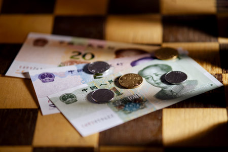 Chinese yuan money on the background of a chess board. Banknotes and coins of yuan from China on chessboardの写真素材
