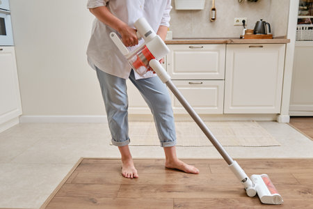 Happy woman with Xiaomi Mi Handheld Vacuum Cleaner G10 cleans home kitchen - Moscow, Russia, June 19, 2022のeditorial素材