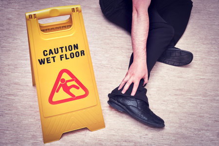 Falls and injuries on the wet floor. The sign on the plate with the text - caution wet floorの写真素材