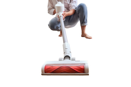 Woman with a wireless portable vacuum cleaner in the kitchen, isolated on a white background. Cleans the floor in an apartment with a vacuum cleaner with a batteryの写真素材