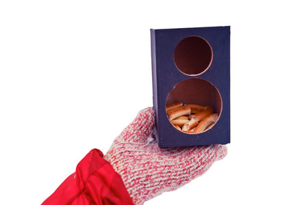 Winter feeder in the snow with bread for birds and woman hand, isolated on a white background. Music column converted into a feeder - secondary use of things, recyclingの写真素材