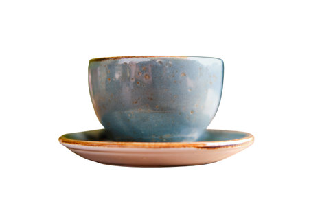 Blue cup, saucer and spoon on a wooden table of a summer cafe, isolated on a white backgroundの写真素材