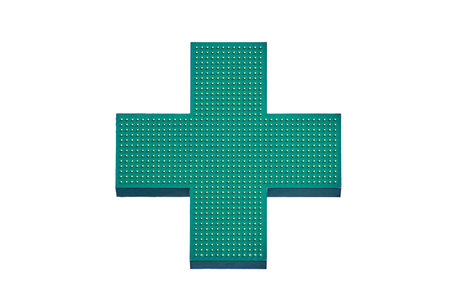 Green cross of a pharmacy store on the wall of a building, isolated on a white backgroundの写真素材