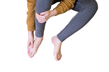 A woman fell from a wooden stepladder and holds on to her sore leg, isolated on a white background. Ladder made of wood broke under a man while working at homeの写真素材