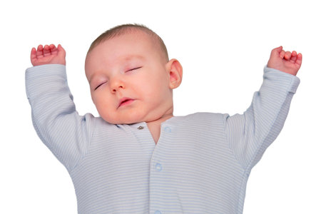 The infant baby sleeps in a star shaped pose with his arms spread out on a child bed, isolated on a...