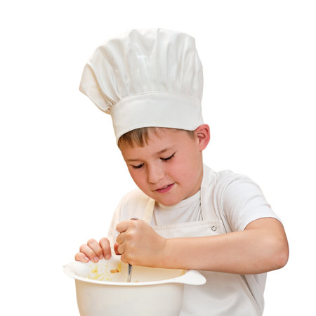 A child boy in white chef's clothes cooks food in a home kitchen, isolated on a white backgroundの写真素材