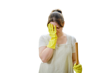 A crying woman holds her head with her hand while cleaning in a home kitchen, isolated on a white backgroundの写真素材