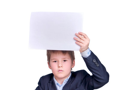 A boy in a school suit with a sheet of A4 paper during distance learning, isolated on a white backgroundの写真素材