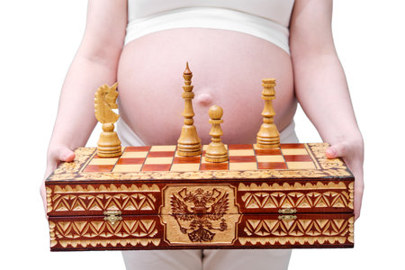 Chess in the hands of a pregnant woman, studio shot, isolated on a white backgroundの写真素材