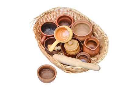 Antique dishes, cups and bowls in a wicker basket, isolated on a white background