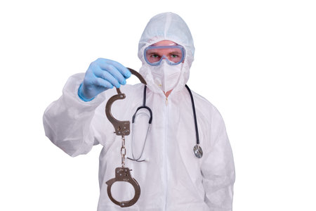 A doctor in a white uniform wearing a medical face mask with handcuffs in his hands, isolated on a white backgroundの写真素材