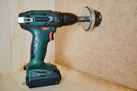 Drilling round holes with a crown on the drill bit. Sawing furniture with a circular saw with a nozzle on an electric screwdriverの写真素材