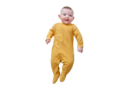 Happy infant baby lies on a blanket in yellow autumn clothes with a red pumpkin, isolated on a white background. Smiling child with orange leaves, top view. Kid aged six monthsの写真素材