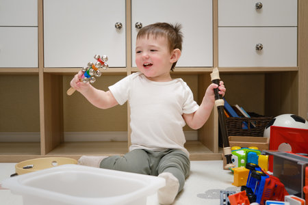 Toddler baby plays the flute sitting on the floor in the children's room. Child boy playing musical instruments. Kid aged one year eight monthsの写真素材
