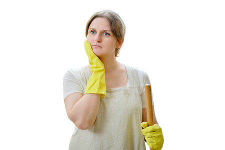 A thoughtful woman in doubt holds her head with her hand while cleaning in the home kitchen, isolated on a white backgroundの写真素材