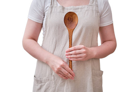 A large wooden spoon in the hands of a woman in the kitchen, isolated on a white background. Women's hands hold a salad spoonの写真素材