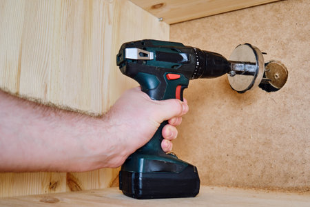 Drilling round holes with a crown on the drill bit. Sawing furniture with a circular saw with a nozzle on an electric screwdriverの写真素材