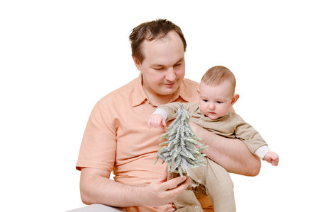 A man father and a boy son play with a small Christmas tree on the sofa in the home living room, isolated on a white background. Kid aged six monthsの写真素材