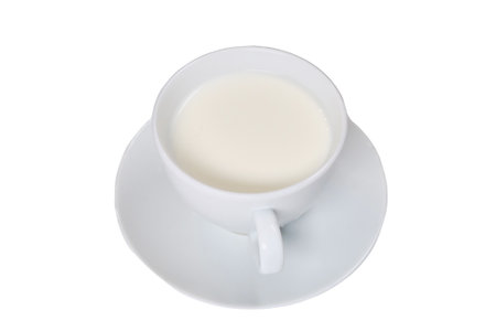 White cup with milk on a saucer, isolated on a white backgroundの写真素材