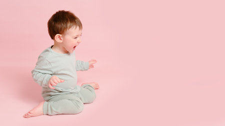 Happy toddler baby on studio pink background, copy space. Emotional child boy with a smile on his face, full height. Kid age one year eight monthsの写真素材