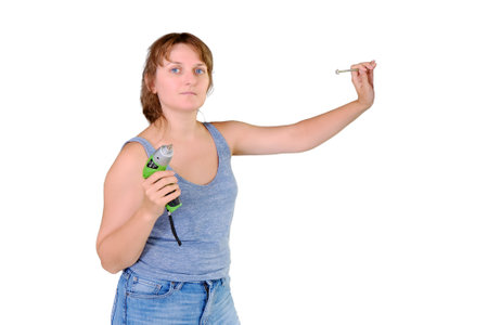 A young woman stands with a screwdriver in a built house, isolated on a white background. How to repair a new apartment yourself, copy spaceの写真素材