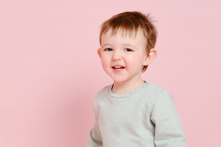 Happy toddler baby on studio pink background, copy space. Emotional child boy with a smile on his face. Kid age one year eight monthsの写真素材