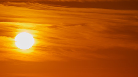 Evening red sun in the clouds at sunset sets over the horizonの写真素材
