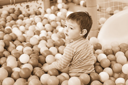 Toddler baby plays in the pool with balls. Child boy crawling in the pool with plastic balls. Kid age one year nine monthsの写真素材