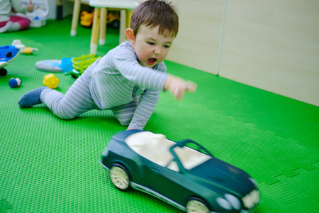 Toddler baby is playing with toys in kindergarten. Happy child boy in the playroom. Kid aged one year nine monthsの写真素材