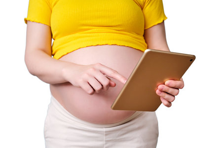 Digital tablet in the hands of a pregnant woman, isolated on a white backgroundの写真素材