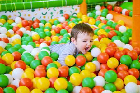 Toddler baby plays in the pool with balls. Child boy crawling in the pool with plastic balls. Kid age one year nine monthsの写真素材